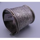 An antique Afghan unmarked silver bracelet with tooled patterning. 5 cm diameter.