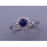 An 18 ct white gold sapphire and diamond cluster ring with diamond shoulders. Ring size M. 2.