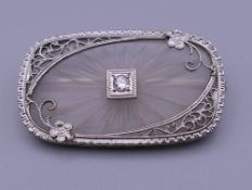 A 14 ct white gold oblong crystal back brooch with solitaire diamond centre. 3 cm wide.