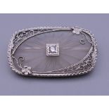 A 14 ct white gold oblong crystal back brooch with solitaire diamond centre. 3 cm wide.