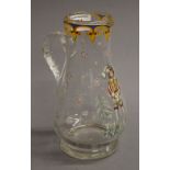 An enamel decorated clear glass ewer. 22 cm high.