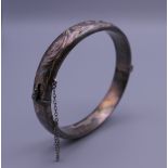 An embossed silver bangle form bracelet. 6.5 cm wide. 15.8 grammes.
