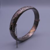 An embossed silver bangle form bracelet. 6.5 cm wide. 15.8 grammes.