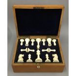 A late 19th/early 20th century oak cased ivory Staunton pattern chess set. The kings 8.5 cm high.