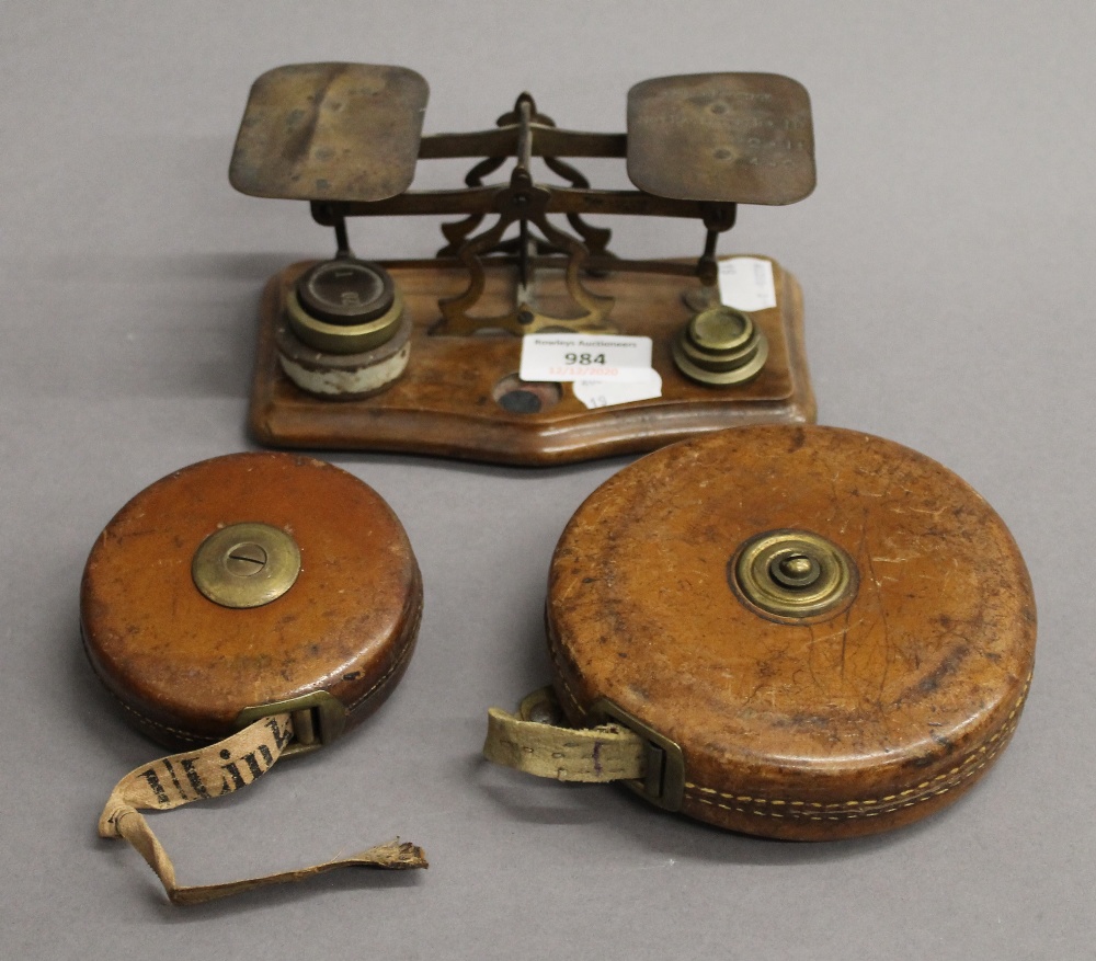 A set of Victorian postal scales and two leather cased tape measures. The former 16 cm wide.