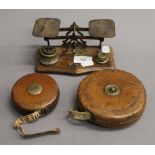 A set of Victorian postal scales and two leather cased tape measures. The former 16 cm wide.