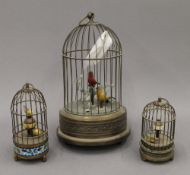 Two brass bird cage clocks and a brass bird cage automaton. The latter 27 cm high.