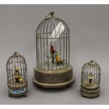 Two brass bird cage clocks and a brass bird cage automaton. The latter 27 cm high.