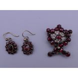 A garnet and seed pearl brooch and a pair of garnet set earrings. The former 2.5 cm high.