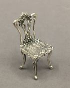 A miniature silver model of a chair. 5 cm high.