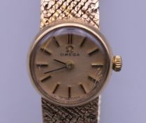 A 9 ct gold Omega ladies wristwatch. 1.5 cm wide. 23.7 grammes total weight.