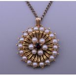 A 9 ct gold seed pearl and garnet pendant on a chain. 2.25 cm diameter. 9.9 grammes total weight.