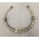 An antique Afghan white metal torc, tooled with glass coloured beads.