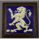 A porcelain tile depicting a rampant lion, set in an oak frame. 28 cm wide.