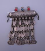 An Afghan white metal amulet with three glass stones. 9 cm long.