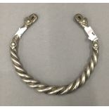 An Afghan white metal torc with twisted wire decoration. 12 cm diameter.