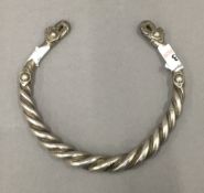 An Afghan white metal torc with twisted wire decoration. 12 cm diameter.