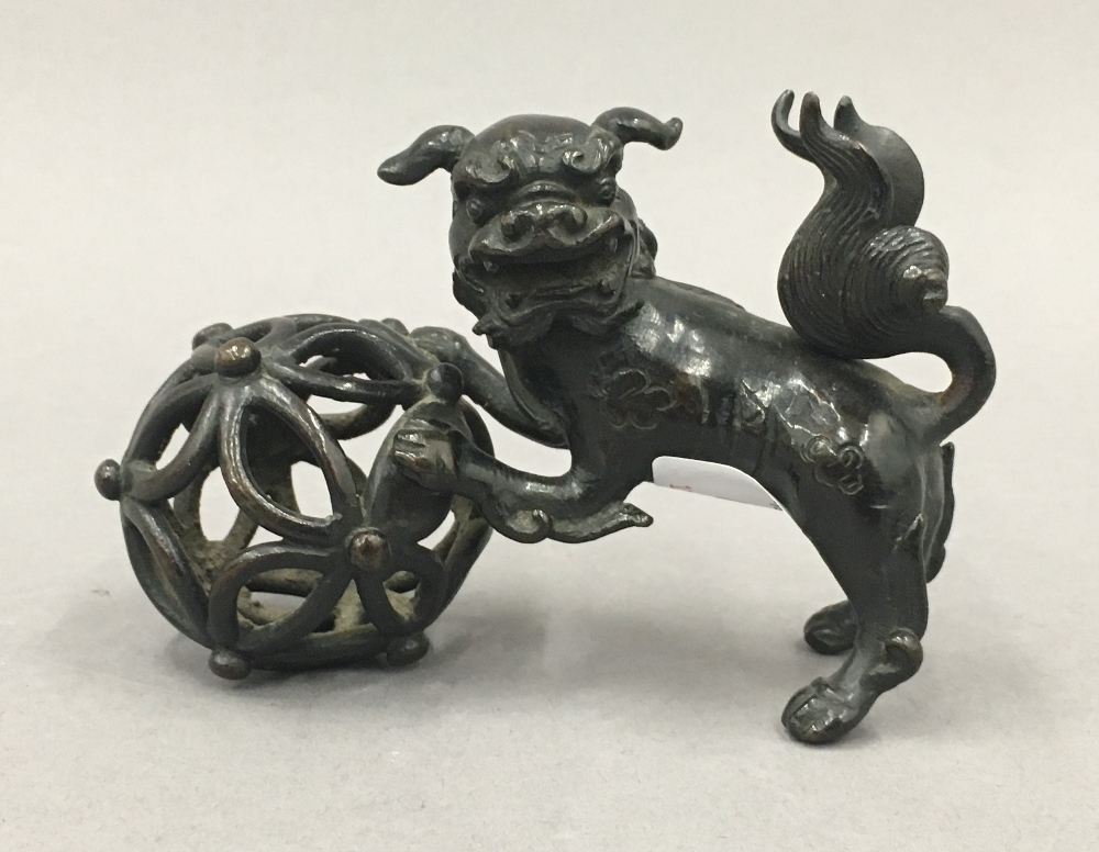 A Chinese patinated bronze model of a dog-of-fo and ball. 11.5 cm long.