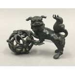 A Chinese patinated bronze model of a dog-of-fo and ball. 11.5 cm long.
