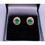 A pair of 18 ct gold emerald and diamond earrings. 1 cm high.