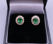 A pair of 18 ct gold emerald and diamond earrings. 1 cm high.