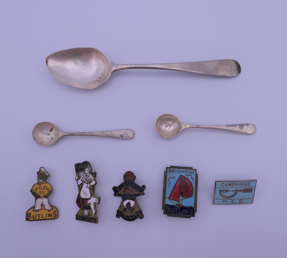 A small quantity of Butlins badges, a pair of silver salt spoons and a silver teaspoon.