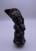 An Indonesian carved wooden kris handle formed as Rangha. 11.5 cm high.