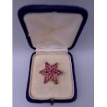 An unmarked gold and ruby star form brooch. 2.75 cm wide. 4.9 grammes total weight.