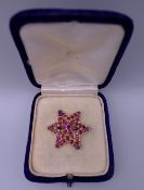 An unmarked gold and ruby star form brooch. 2.75 cm wide. 4.9 grammes total weight.