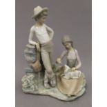 A Lladro porcelain group formed as a young shepherd and shepherdess feeding a lamb. 27 cm high.