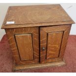 Edwardian oak table/smokers cabinet enclosed by two panelled cupboard doors with fitted interior,