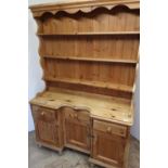 Pine dresser with recessed centre, and three drawers above three cupboard doors (width 130cm x