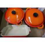 A burnt orange color le cruset shallow twin handled pan and lid and another large pan and a