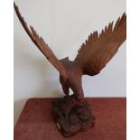 Large carved oak figure of an eagle with outspread wings on branch and rocky outcrop (repair to