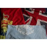 Small mid 20th C British flag on staff, a UN flag, a large Royal Artillery flag, and another British