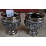 Pair of Indian white metal vases with embossed detail of various goddess type figures (6cm high)