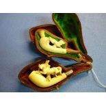 Cased carved bone Meerschaum type pipe with the figure of a dog, and another carved bone pipe with