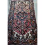20th C red ground Persian patterned carpet with floral border (194cm x 115cm)