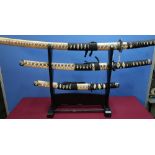 Set of three decorative Japanese style samurai swords with stand