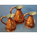 Copper gallon rum flagon with loop handle and two similar half gallon flagons (3)