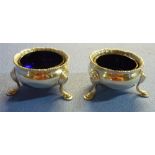 Pair of London 1935 silver hallmarked salts mounted on three hoof feet with blue glass liners,