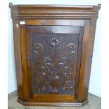 19th C oak wall mounted corner cabinet enclosed by a single carved panelled cupboard door