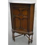 Early 20th C oak free standing corner unit enclosed by panelled cupboard door, on turned supports (