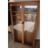 Early to mid 20th C oak gun style cabinet enclosed by two glazed doors with internal shelf and gun