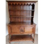 Oak dresser with two tier raised back above two panelled cupboard doors with under tier on turned