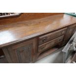 Large oak sideboard with raised back above two central drawers and open shelf, flanked by two carved