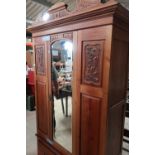 Late Victorian beech wardrobe enclosed by single bevelled edge mirrored door with carved and