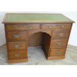 Edwardian oak knee-hole desk, with inset leather top above eight drawers with brass handles,
