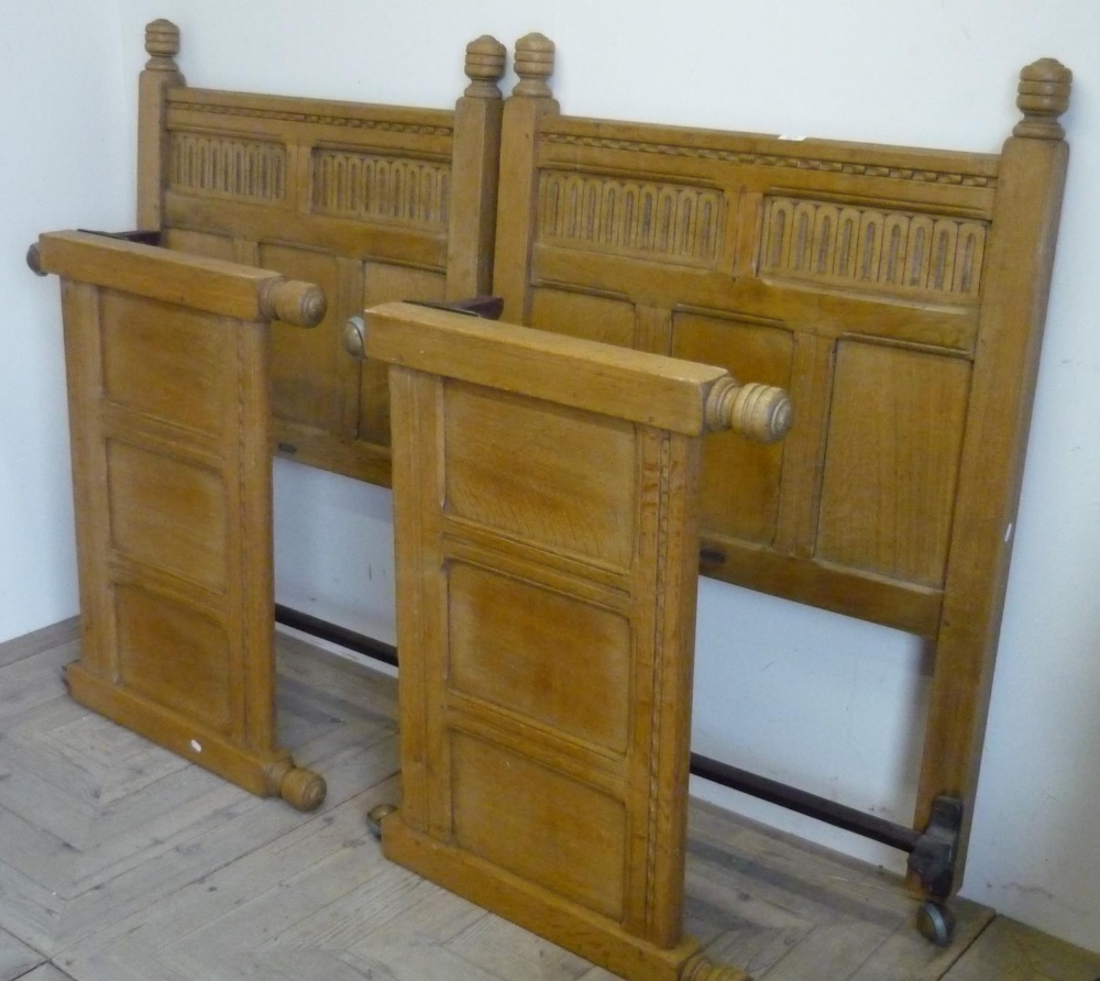 Pair 20th Century Jacobean style light oak single bedsteads with carved and panel head and foot-