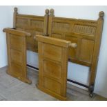 Pair 20th Century Jacobean style light oak single bedsteads with carved and panel head and foot-